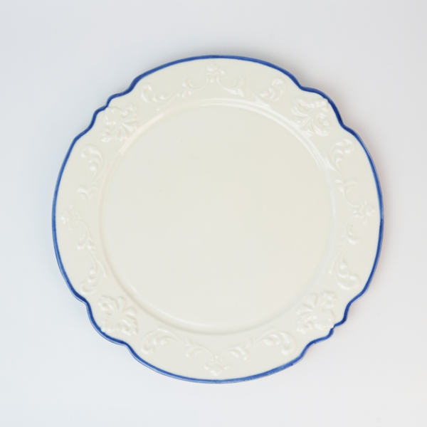 A round plate with white clay elements and a blue rim